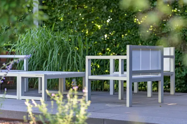 Tuinstoelen op een terras van grijze tegels, met een haag op de achtergrond